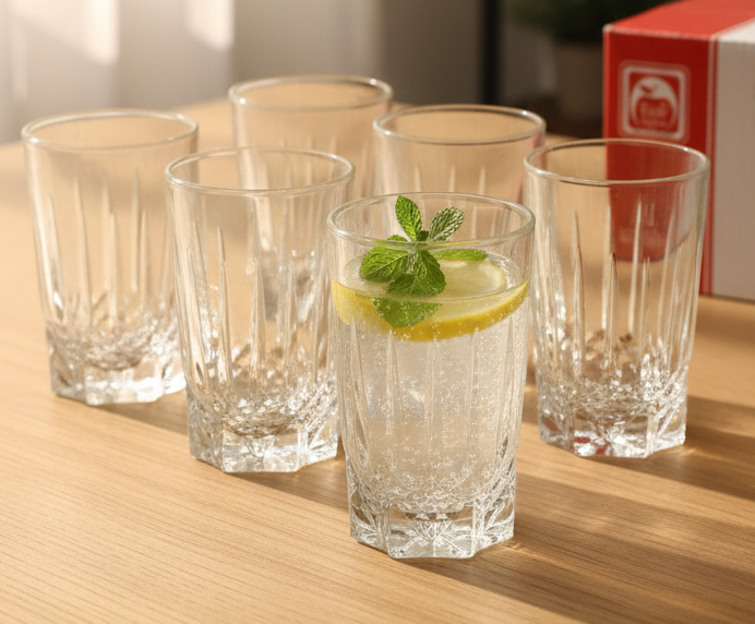 Set of clear glasses on a wooden surface with one containing a lemon and mint garnish.